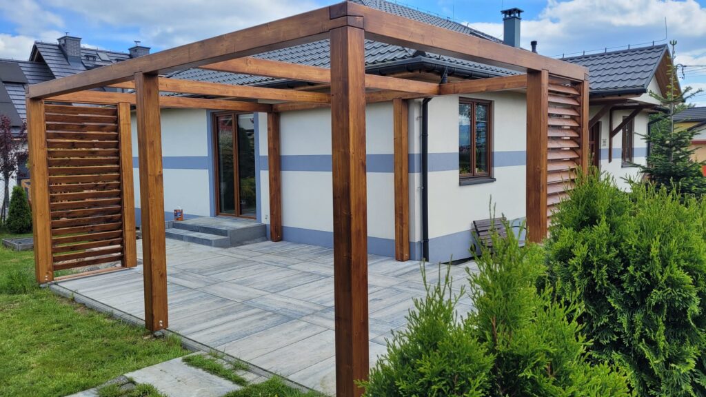 Nowoczesna pergola tarasowa przy domu - zadaszenie z drewna i roletami